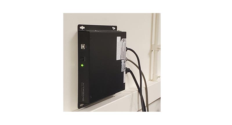 J60 lithium UPS wall-mounted on wall with bracket hardware visible — green status LED lit, cables connected, Xtreme Power branding visible