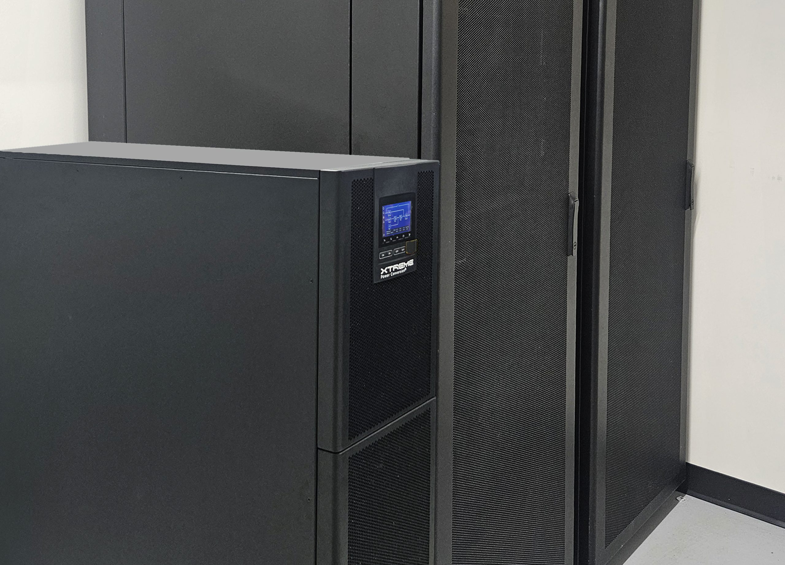 Li90 three-phase lithium UPS installed between server racks in data center — slim 12.6 inch cabinet with touchscreen display visible