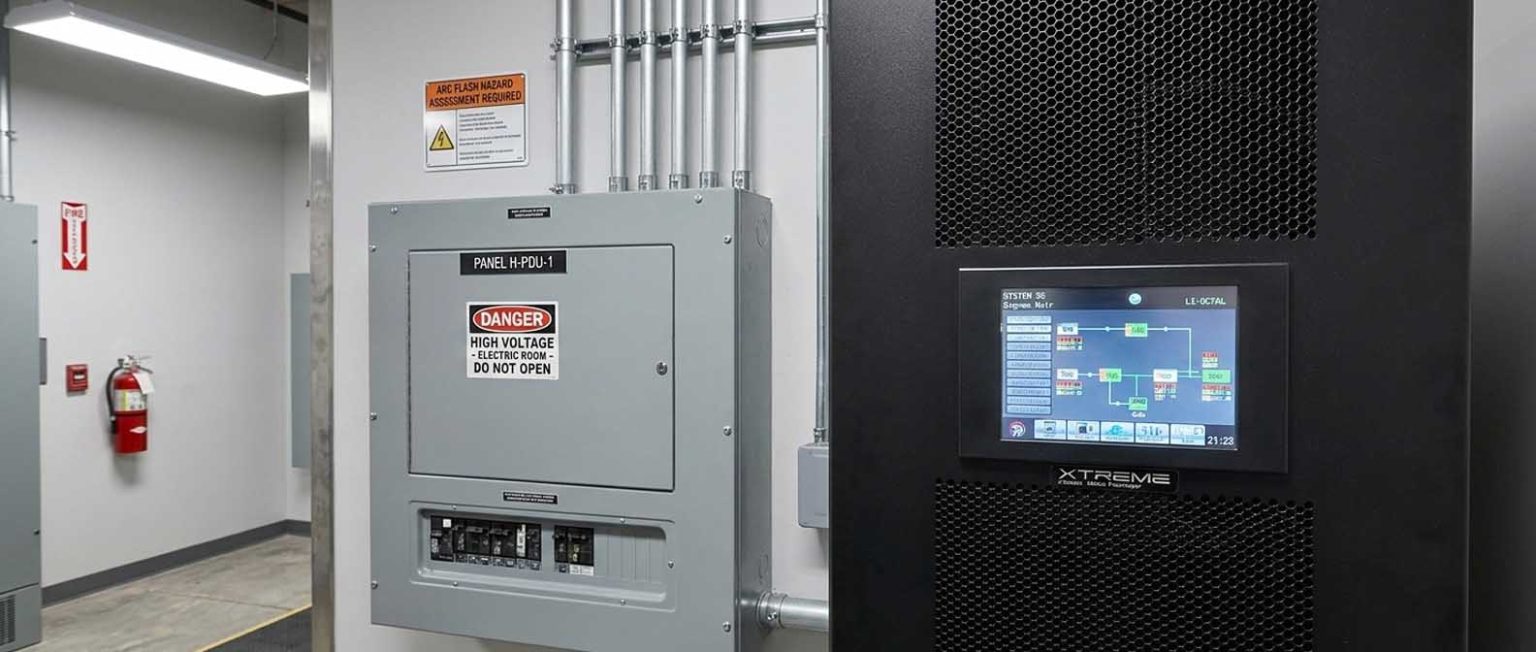 Hospital electrical room with Panel H-PDU-1 distribution panel and X90-2S modular UPS — Xtreme Power touchscreen showing system one-line diagram, arc flash warning posted