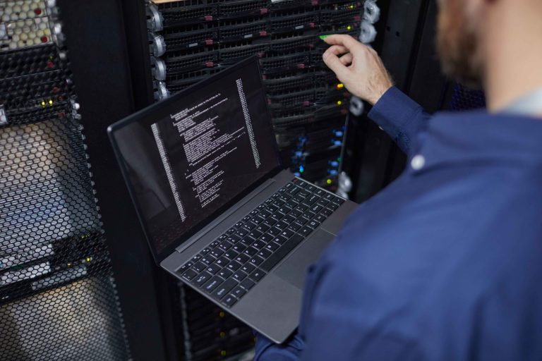 IT technician servicing rack infrastructure with a laptop in a data center