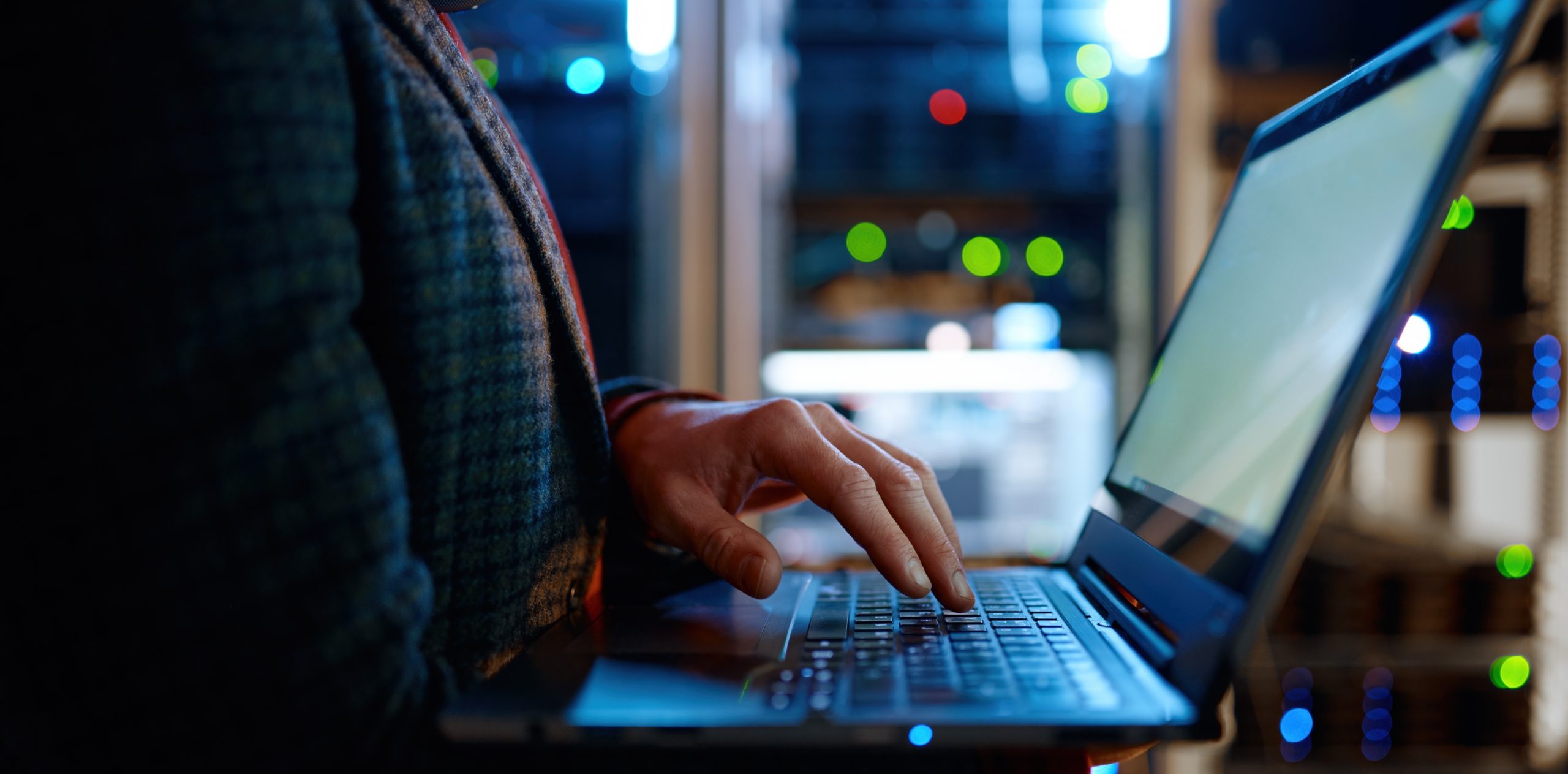 Data center technician evaluating infrastructure with a laptop in a server environment