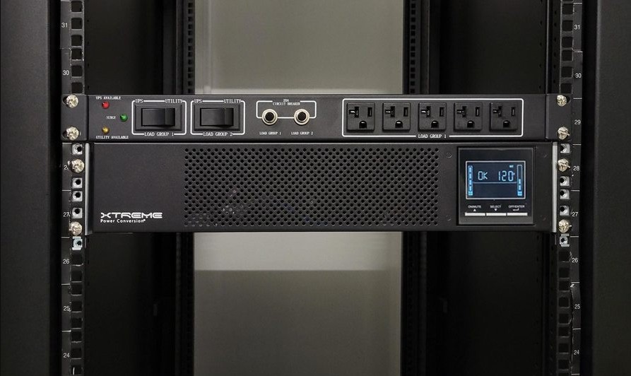 Xtreme Power XBDM-1030LV maintenance bypass module rack-mounted directly above a P91 3000 VA UPS, showing the UPS/Utility load-group bypass switches, 20A circuit breaker, status LEDs, and output receptacles
