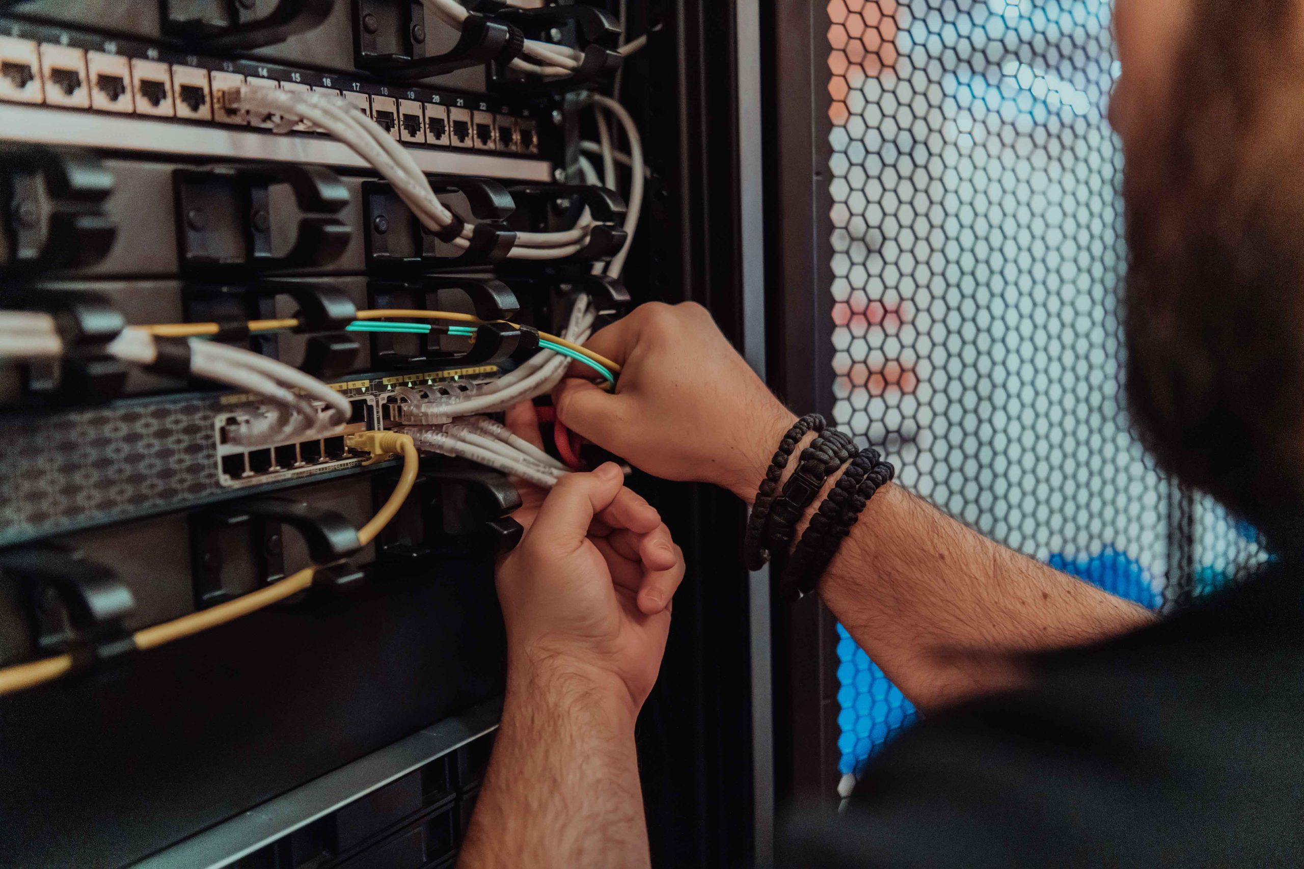 IT technician servicing rack infrastructure with a laptop in a data center